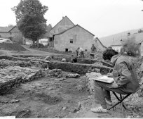 Slika 2: Arheološka izkopavanja na Hrušici leta 1973, pri katerih so sodelovali Narodni muzej Slovenije, Univerza v Münchnu in domačini. Spredaj arheolog riše izkopane zidove, v  ozadju je ekipa. Arhiv NMS, avtor Srečo Habič.
