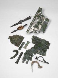 Slika 3: Vojaška oprema, ki so jo našli na Hrušici. Zgoraj levo dve osti kopja, v sredini dva dela oklepa in okovi za vojaški pas, spodaj desno zaponki za obleko. Arhiv NMS, avtor Tomaž Lauko.